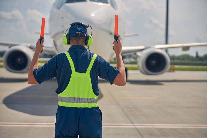 worker signally plane landing on runway